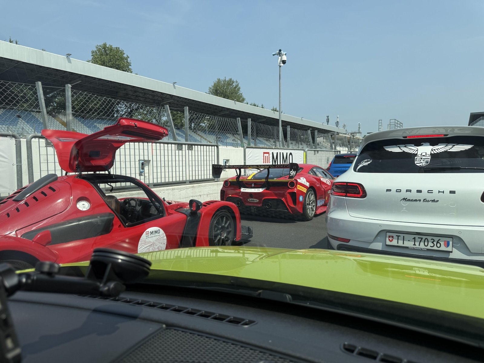 Vista dall'abitacolo dell'Abarth 600e in coda alla MIMO Parade tra una Radical RXC Spyder, una Ferrari 296 Challenge e una Porsche Macan Turbo